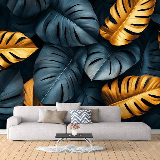 A room with a large sofa and a wall covered in a blue and gold Monstera leaf patterned wallpaper.