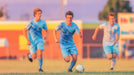 Painterly soccer mural featuring three players in sky blue kits moving across a golden field