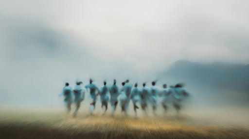 Abstract impressionist mural featuring blurred human figures emerging from gray fog over a warm golden earth tone.