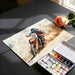 Painting of a motocross rider on a textured surface with a paint palette and rose.