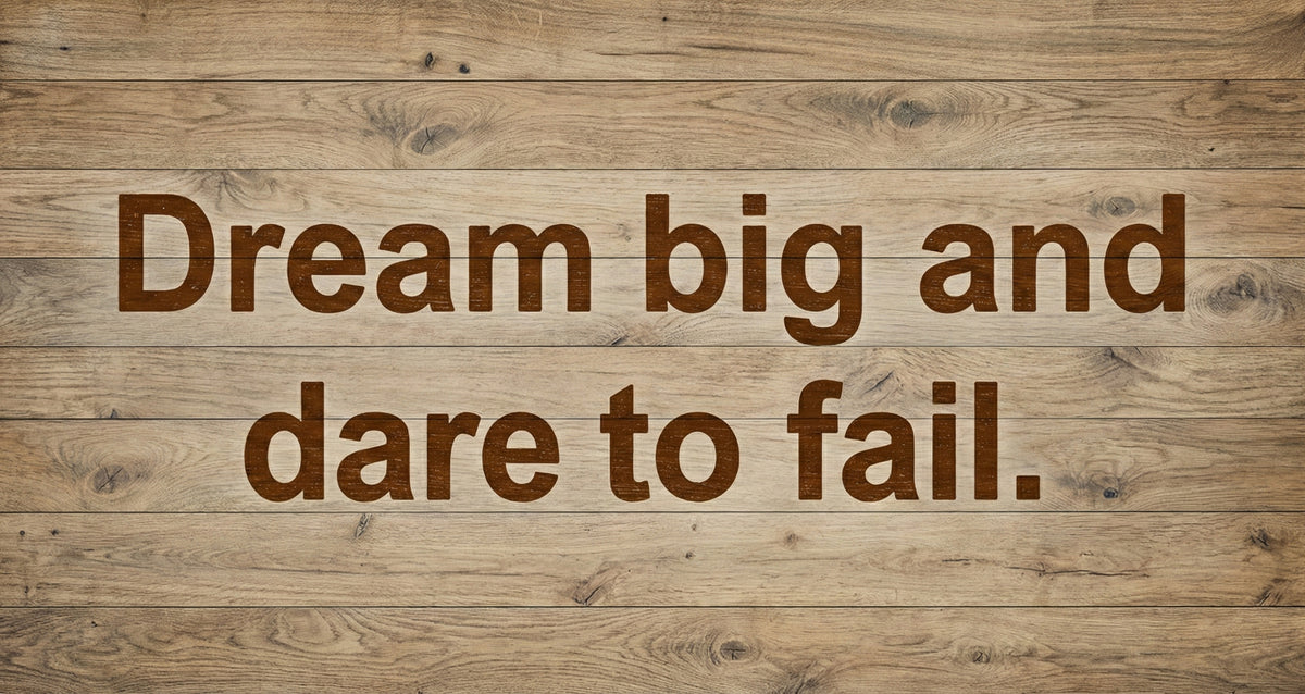 Rustic light wood grain pattern with bold, deep espresso typography reading Dream big and dare to fail