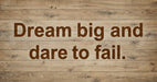 Rustic light wood grain pattern with bold, deep espresso typography reading Dream big and dare to fail