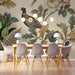 A sophisticated dining room featuring pheasant and floral wallpaper as a feature wall behind a wooden table.