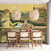 A cozy kitchen dining area featuring a Mediterranean landscape mural behind a wooden table.