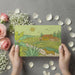 Whimsical country landscape wallpaper in a bright, modern nursery