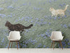 Whimsical cat meadow mural installed in a light-filled nursery with minimalist wooden furniture.