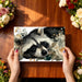 A playful reading nook with raccoon-themed floral mural wallpaper and a comfortable armchair
