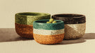 Watercolor style illustration of three textured ceramic bowls in moss green, charcoal, and ochre on a cream background.