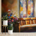 A cozy reading nook features the stained glass floral mural as a backdrop behind a wooden bench.