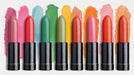 A vibrant mural pattern of lipstick tubes in various shades with matching acrylic paint brushstrokes behind each one.