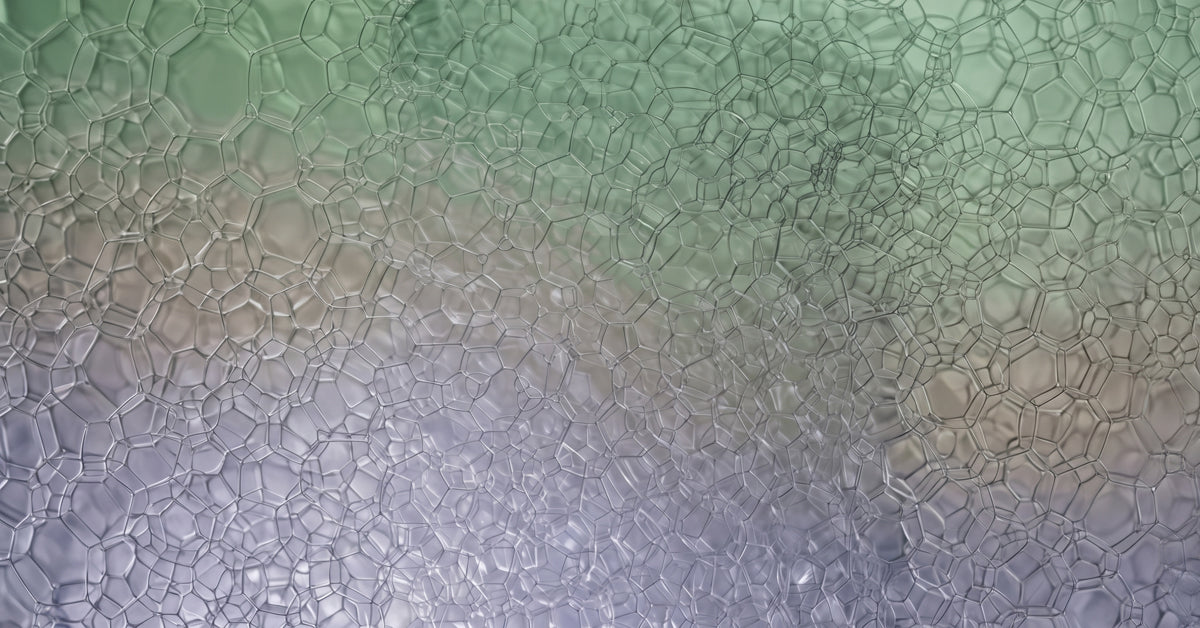 Macro photograph of delicate soap bubble foam in sage green and lavender gradients