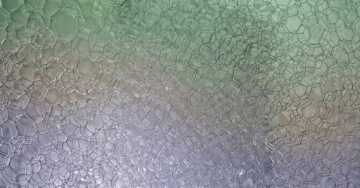 Macro photograph of delicate soap bubble foam in sage green and lavender gradients