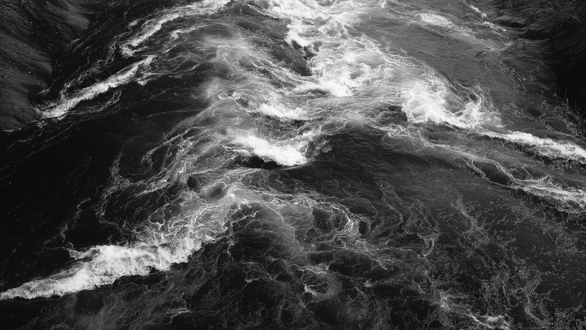 Monochrome mural pattern of churning dark river water with white foam crests