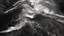 Monochrome mural pattern of churning dark river water with white foam crests