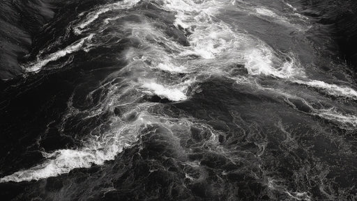 Monochrome mural pattern of churning dark river water with white foam crests