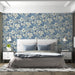 A formal bedroom decorated with blue floral damask wallpaper behind a velvet sofa.