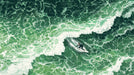 Aerial view of an emerald green ocean wave with a surfer carving a line in an artistic illustration style