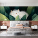 A bedroom wall mural featuring a cat resting in botanical leaves.