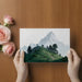 A serene home office with an alpine mountain mural creating a wide-open feeling behind a wooden desk.