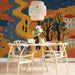 Dining room interior featuring a decorative folk art river landscape mural behind a minimalist beige sofa.