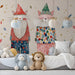 A cozy bedroom featuring a wall with playful cat gnome wallpaper and light wooden furniture.