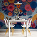 Playful floral dreamscape mural wallpaper installed in a colorful dining room with soft textile bedding.