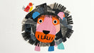 Abstract lion collage mural with charcoal mane, orange face, and red bird on white background