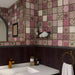 A cozy washroom space with the vintage tiled mosaic mural on the back wall above white cabinets.