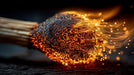 Macro close-up of a lit matchstick with glowing orange sparks and charred wood textures