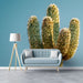 A sunlit entryway showing a tall cactus mosaic wallpaper mural above a wooden sideboard.