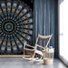 A minimalist study featuring a dramatic symmetrical mural behind a sleek dark sofa.