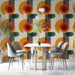 Mid-century modern dining room with geometric orange and green wallpaper behind a tan sofa