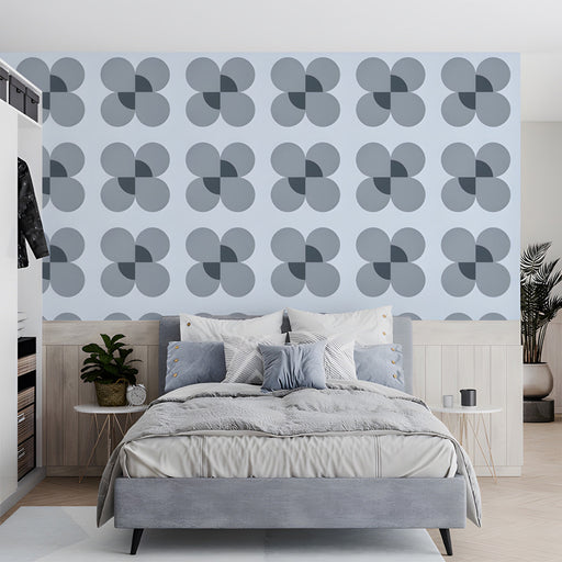 A clean bedroom with a geometric petal wall mural and light wood furniture.