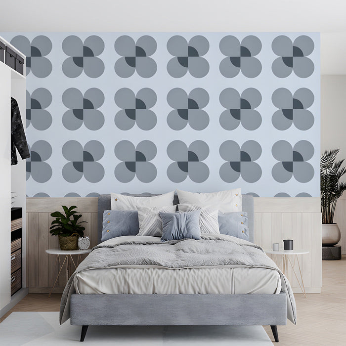 A clean bedroom with a geometric petal wall mural and light wood furniture.