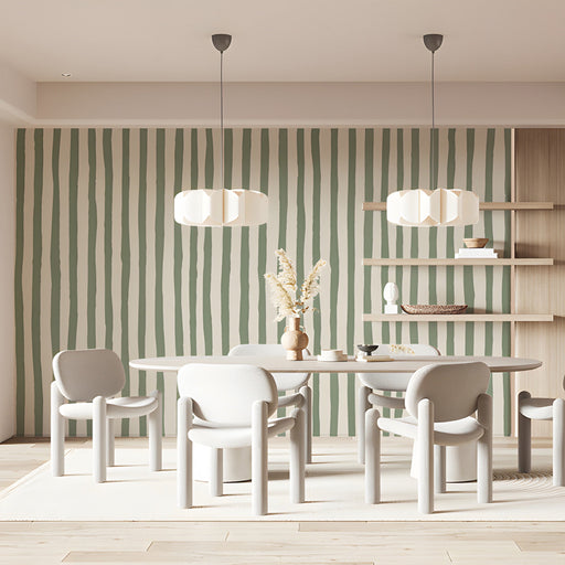 A cozy home office with sage green striped wallpaper on a feature wall behind a wooden desk.