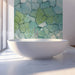 Glacial stone mosaic wallpaper installed in a calming bathroom with light wood furniture.