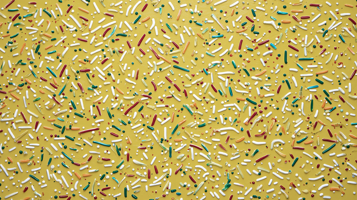 Ochre yellow mural wallpaper featuring scattered white, green, and red paint-like sprinkles