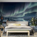 A cozy bedroom wall featuring a glowing cabin in a snowy landscape mural under the aurora borealis.