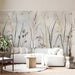 A bright living room featuring a watercolor meadow grass mural wall behind a cream upholstered bed.