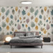 Soft watercolor leaf mural installed as an accent wall in a cozy bedroom with wooden furniture