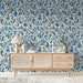 A  bedroom or library wall covered in classic blue trailing leaf mural wallpaper.