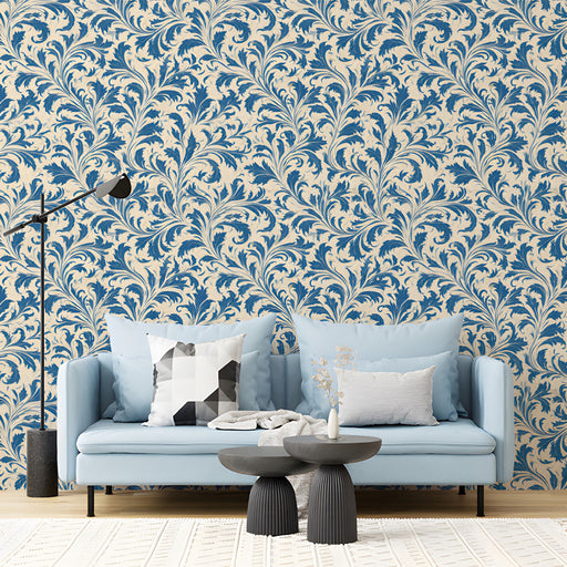 A living room featuring heritage blue leaf wallpaper behind a velvet sofa.