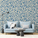 A living room featuring heritage blue leaf wallpaper behind a velvet sofa.