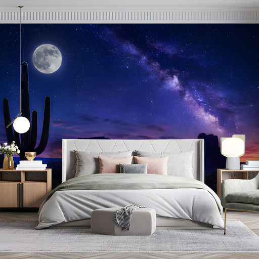A relaxing lounge or bedroom area with a dark celestial desert mural behind velvet armchairs