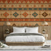 A cozy living room featuring a southwestern geometric wallpaper mural behind a velvet sofa