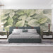 Leaf patterned wall mural in a minimalist bedroom with natural light and house plants