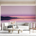Soft gradient pink wall mural behind a lounge chair in a living room