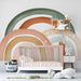 Boho style nursery wall featuring a soft rainbow mural arch pattern