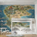 A cozy bedroom featuring a large prehistoric map mural behind a dark wood desk and leather armchair.