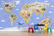 World map mural installed in a bright nursery with light wood furniture and soft cream bedding